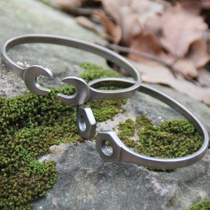 Ambiance stylée avec le jonc double clé plate en acier inoxydable argenté de Rouille, combiné à un jonc en forme d'écrous pour un effet maximal.