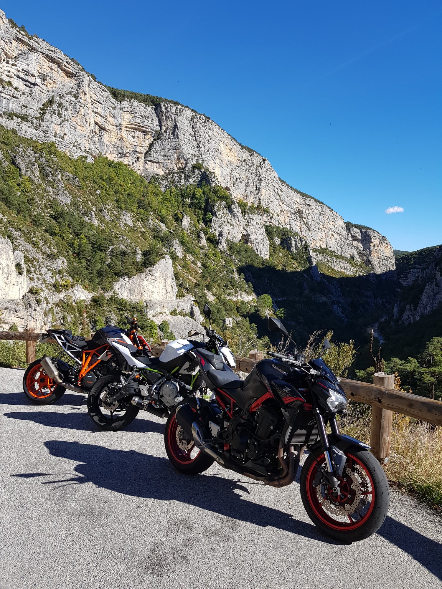 Photo de 3 motos arrêtées devant un paysage de montagne. Une KTM 1290 superduke, une kawasaki Z650 et une kawasaki Z900. 