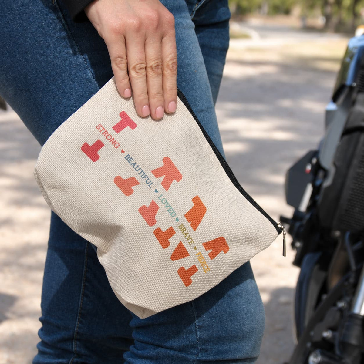 Pochette écrue Je suis forte, belle… tenue par sa dragonne, cadeau original pour motarde.
