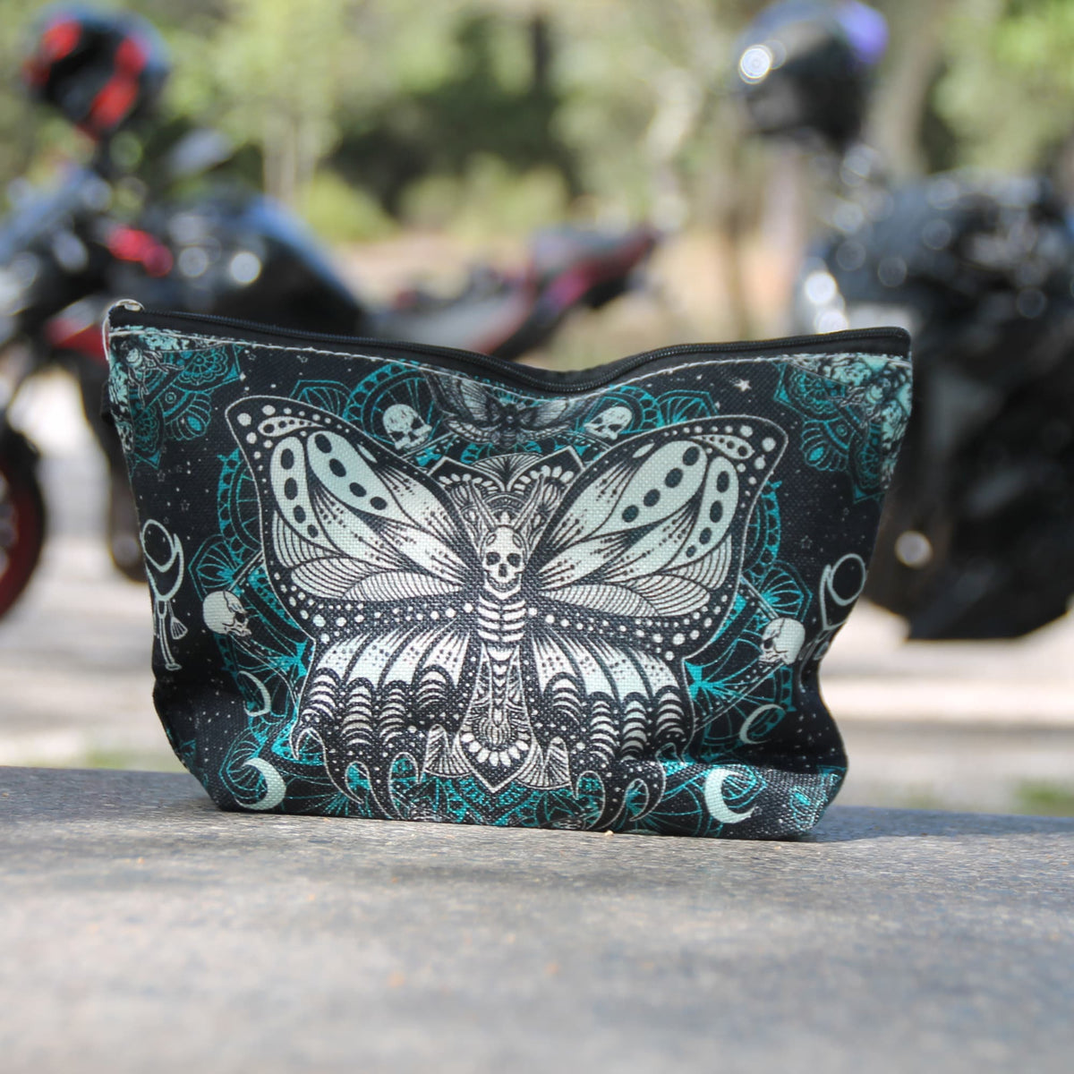 Pochette motarde Papillon Mandala noire et turquoise photographiée devant des motos