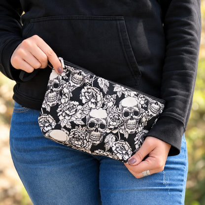 Pochette noire à imprimé floral et crânes blancs tenue en mains, accessoire rock pour motarde.