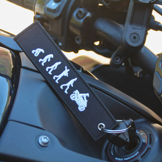 Porte clé moto tissu noir brodé évolution de l'homme jusqu'à devenir motard