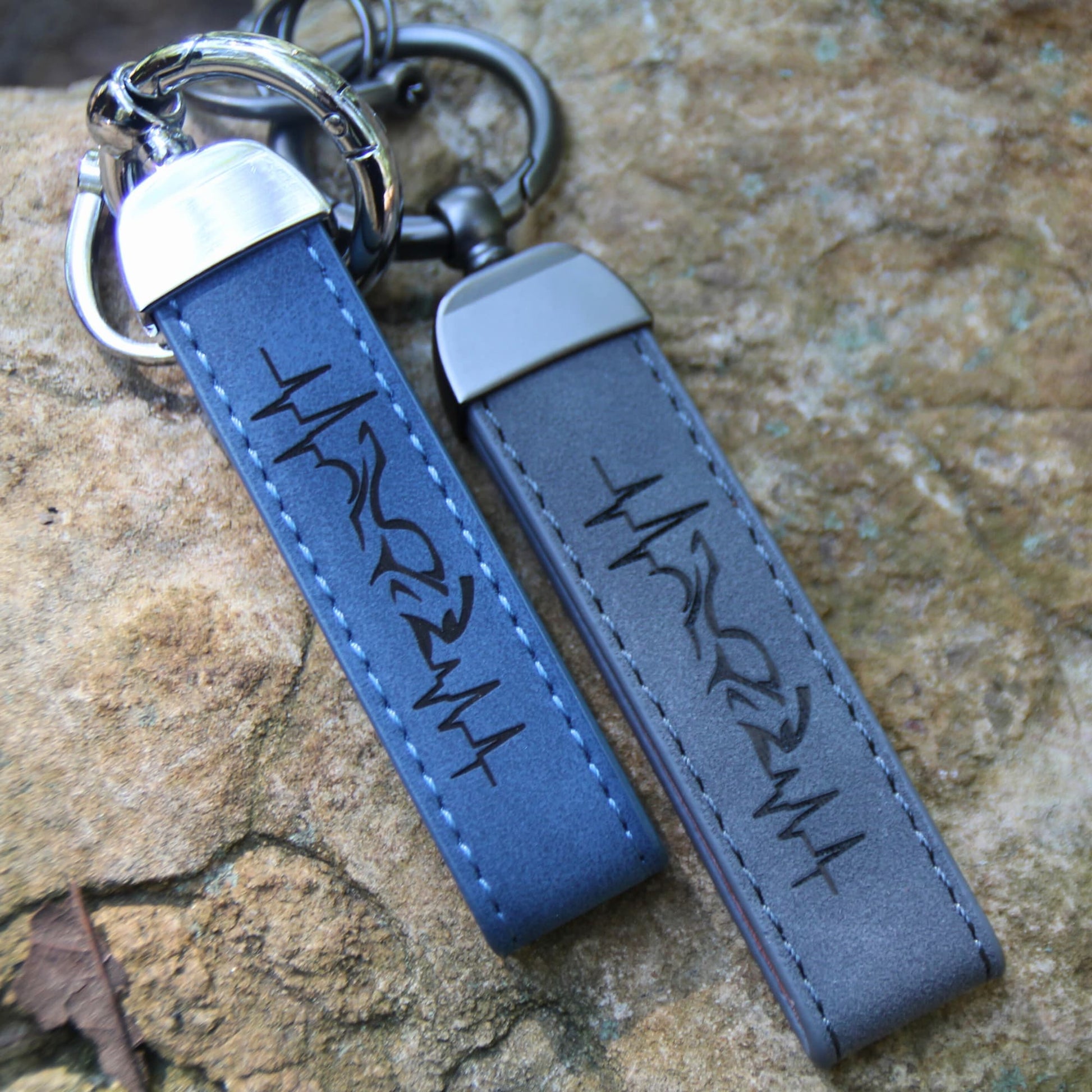 Duo de porte clés en simili cuir gravé d'une ligne de vie traversant une moto.