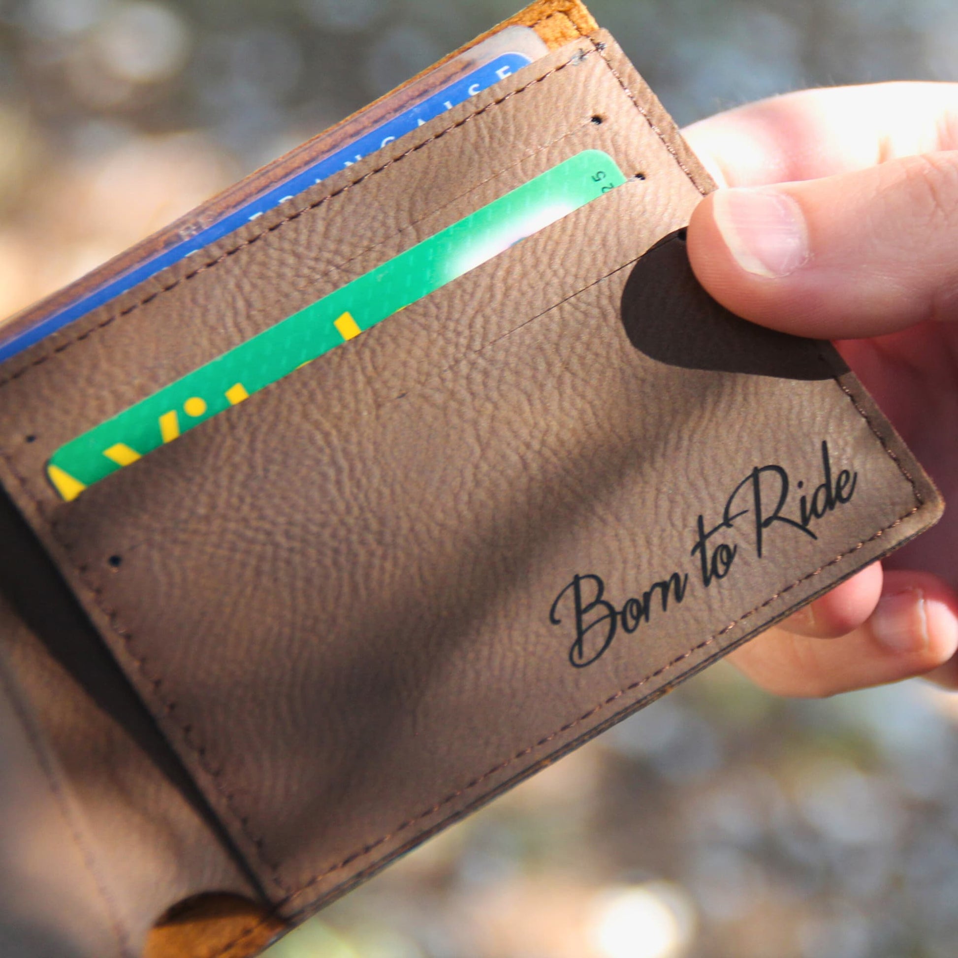Zoom sur le compartiment avec la gravure "Born to Ride" et des cartes insérées, mettant en avant la personnalisation.