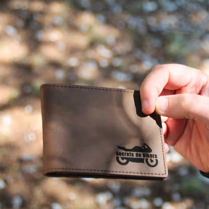 Portefeuille en simili cuir marron fermé, tenu en main, affichant le logo "Secrets de Bikers" sur le devant.