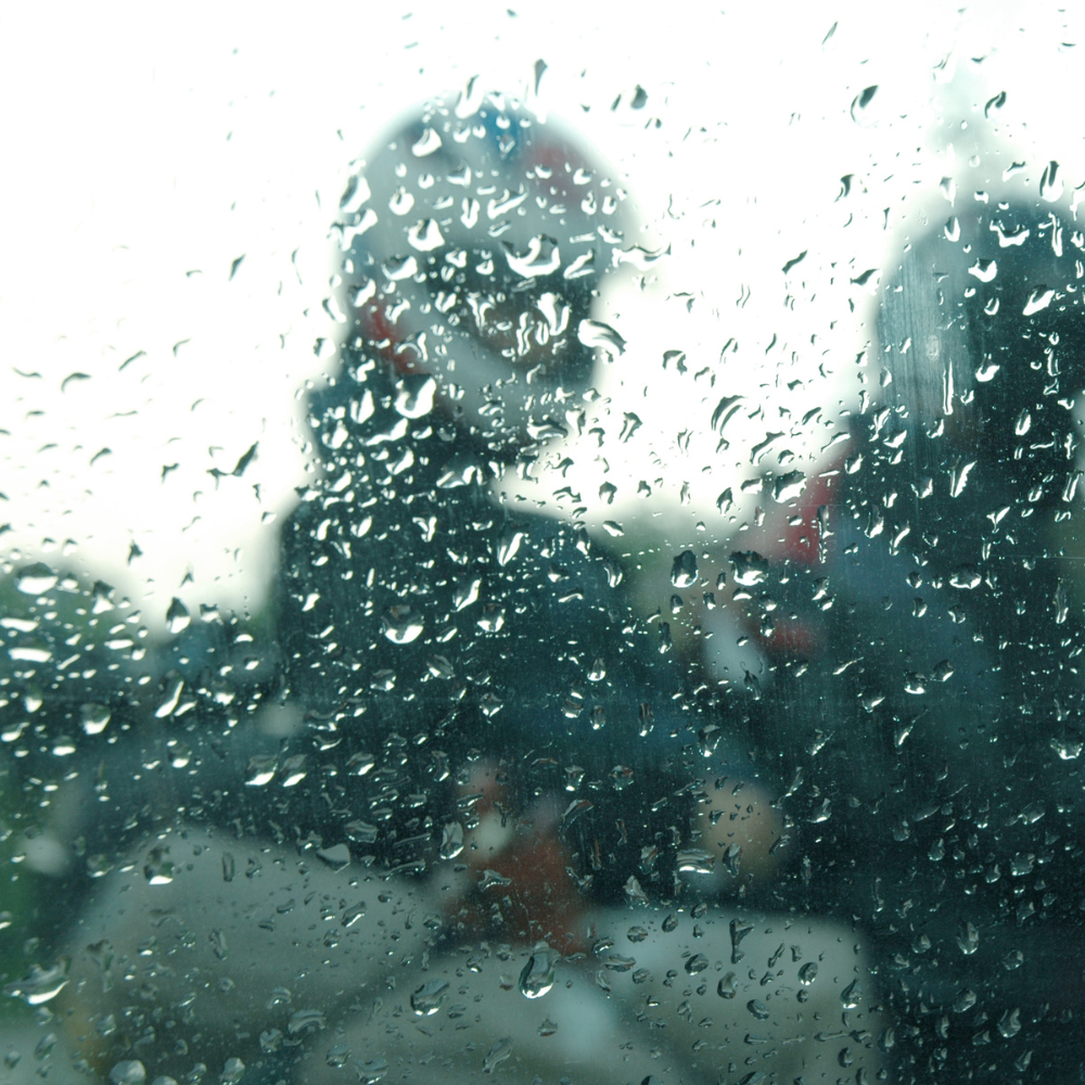 Illustration de goutes de pluie sur une fenêtre devant des motards. 