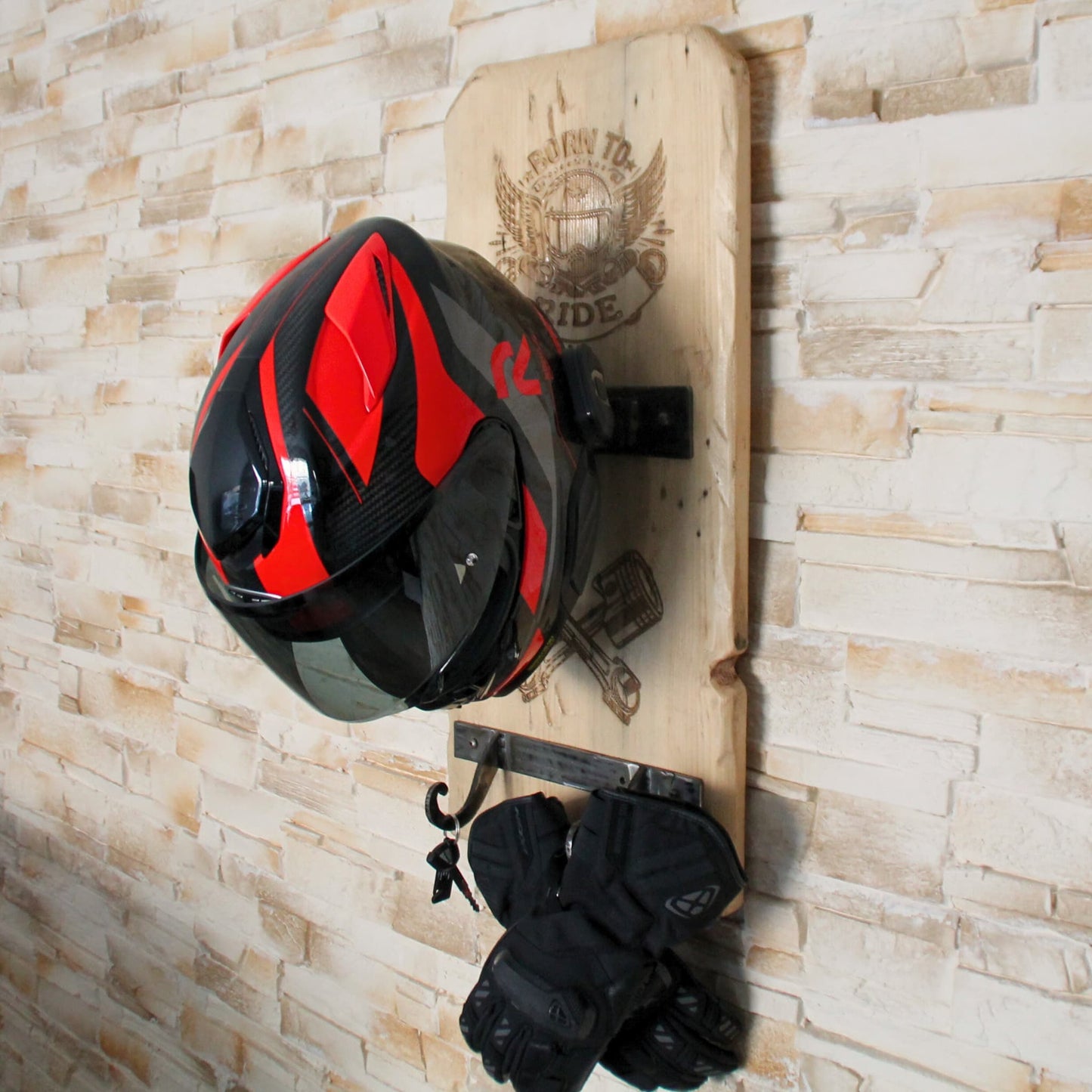Support de casque moto artisanal en bois en situation, avec casque, gants et clés accrochés, idéal pour un espace de moto décoratif et fonctionnel.