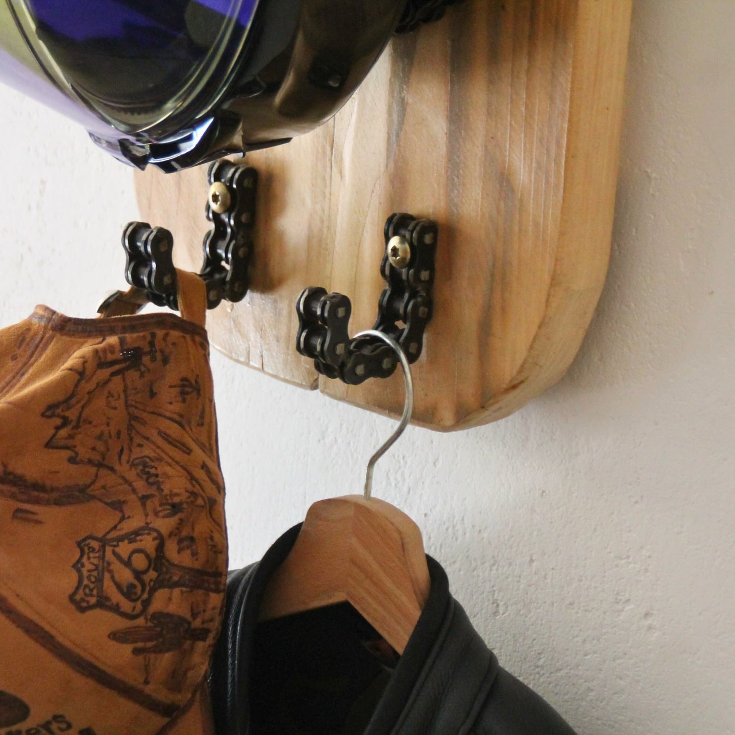 Rangement complet de l'équipement moto (casque, veste, gants) sur le support artisanal.