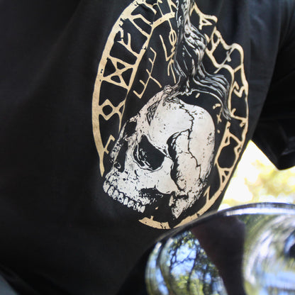 Gros plan sur le motif d'un crâne et d'un corbeau sur un t-shirt noir.