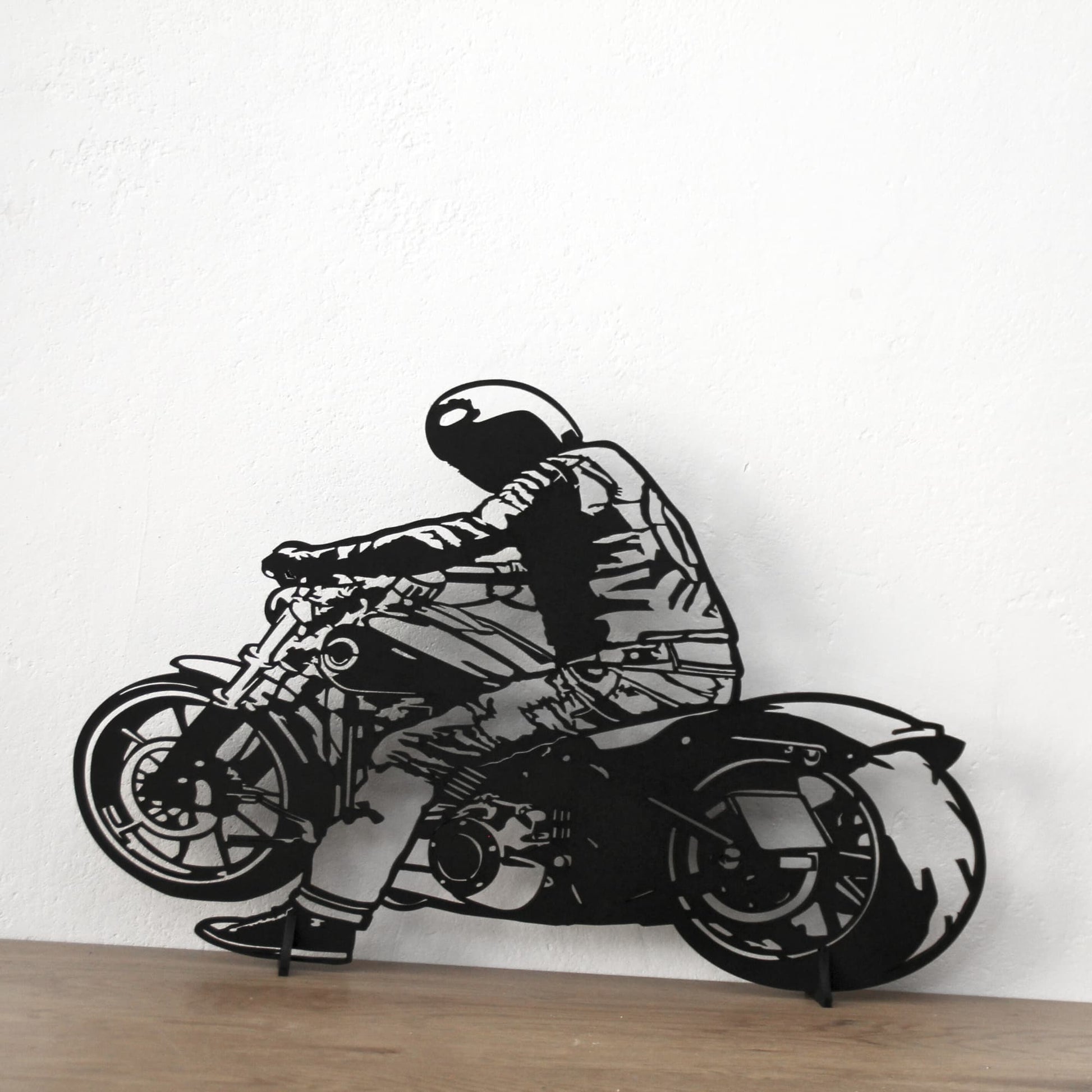 Décoration murale en bois noir représentant un motard, fixée sur un mur aux teintes blanc.