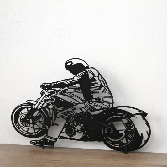 Décoration murale en bois noir représentant un motard, fixée sur un mur aux teintes blanc.