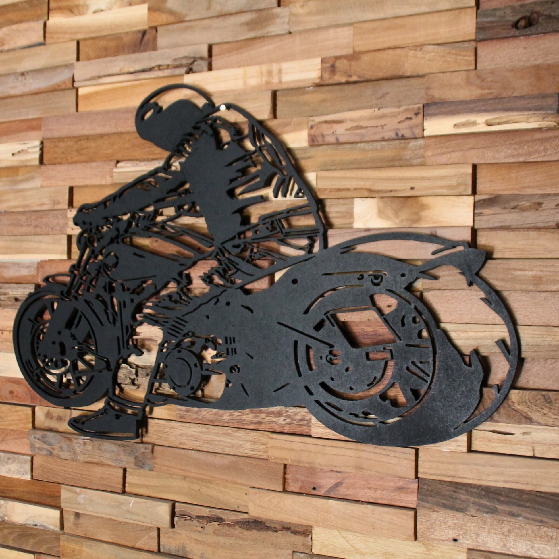 Tableau mural en bois représentant un biker sur sa moto, accroché sur un mur en bois – vue intérieure.