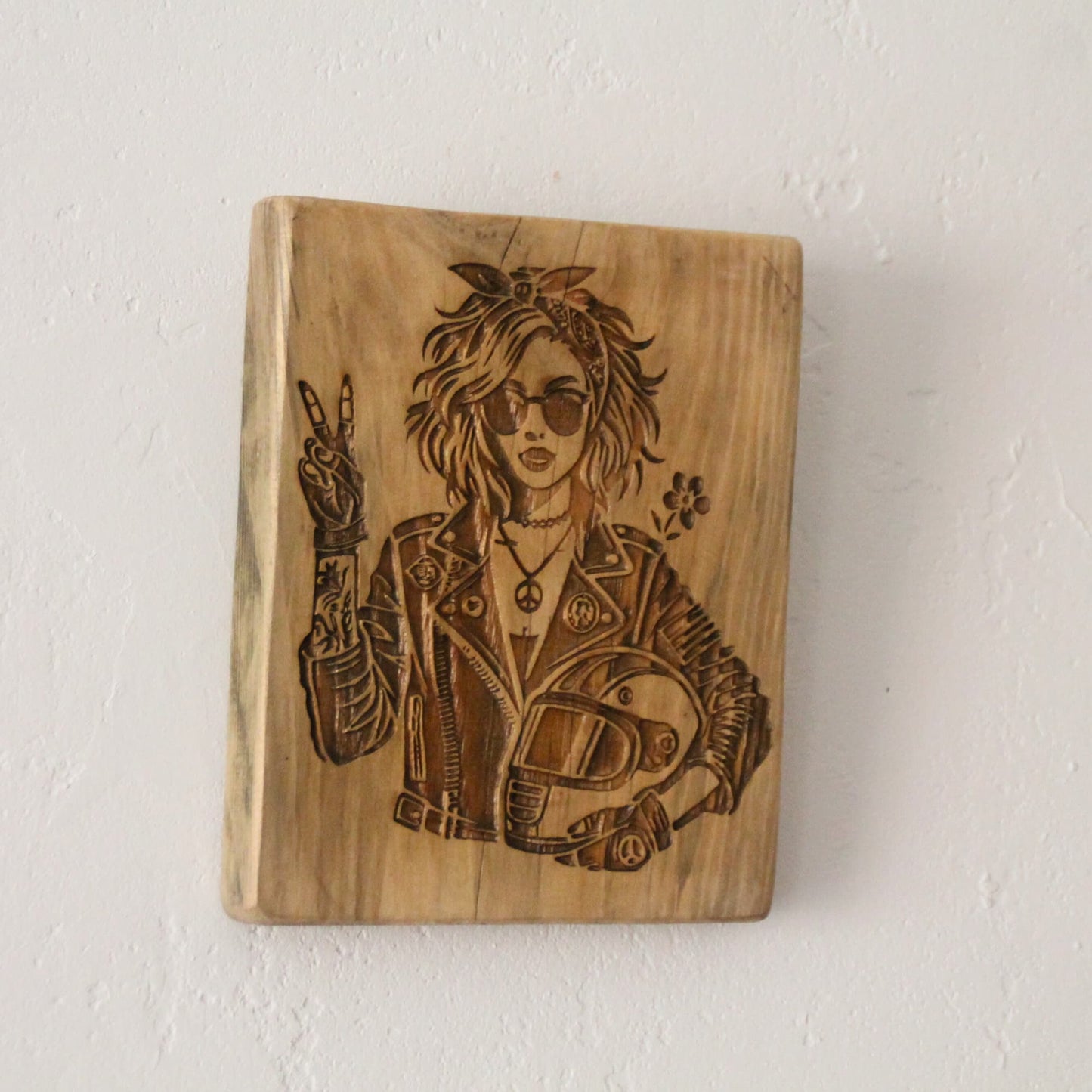 Tableau artisanal en bois brut et gravure motarde signe V sur mur blanc