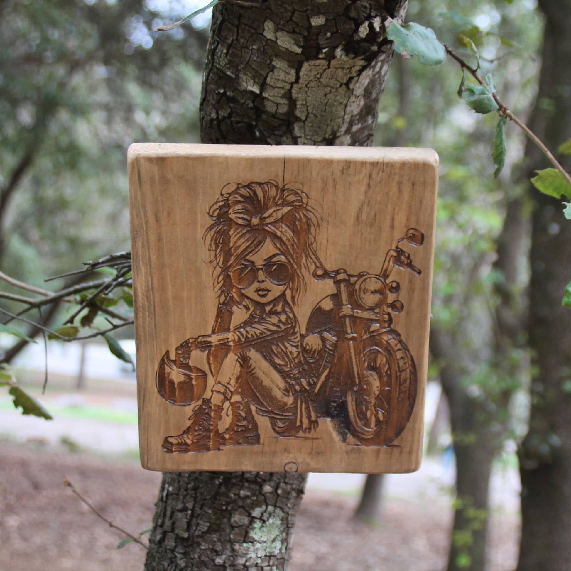 Tableau artisanal en bois gravé d'une motarde caricaturale. Piece unique