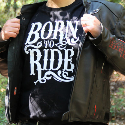 T-shirt "Born To Ride" visible sous une veste en cuir ouverte, style motard vintage.