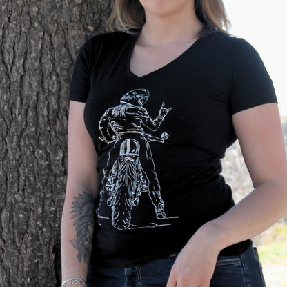T-shirt femme en coton noir, avec une illustration unique représentant une motarde faisant un signe rock de la main. Col en V et tissu 100% coton épais pour un confort et un look durable.