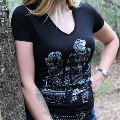 T-shirt col V 100% coton pour femme, porté par une motarde baroudeuse en train de boire un café sur sa moto chargée de bagages.