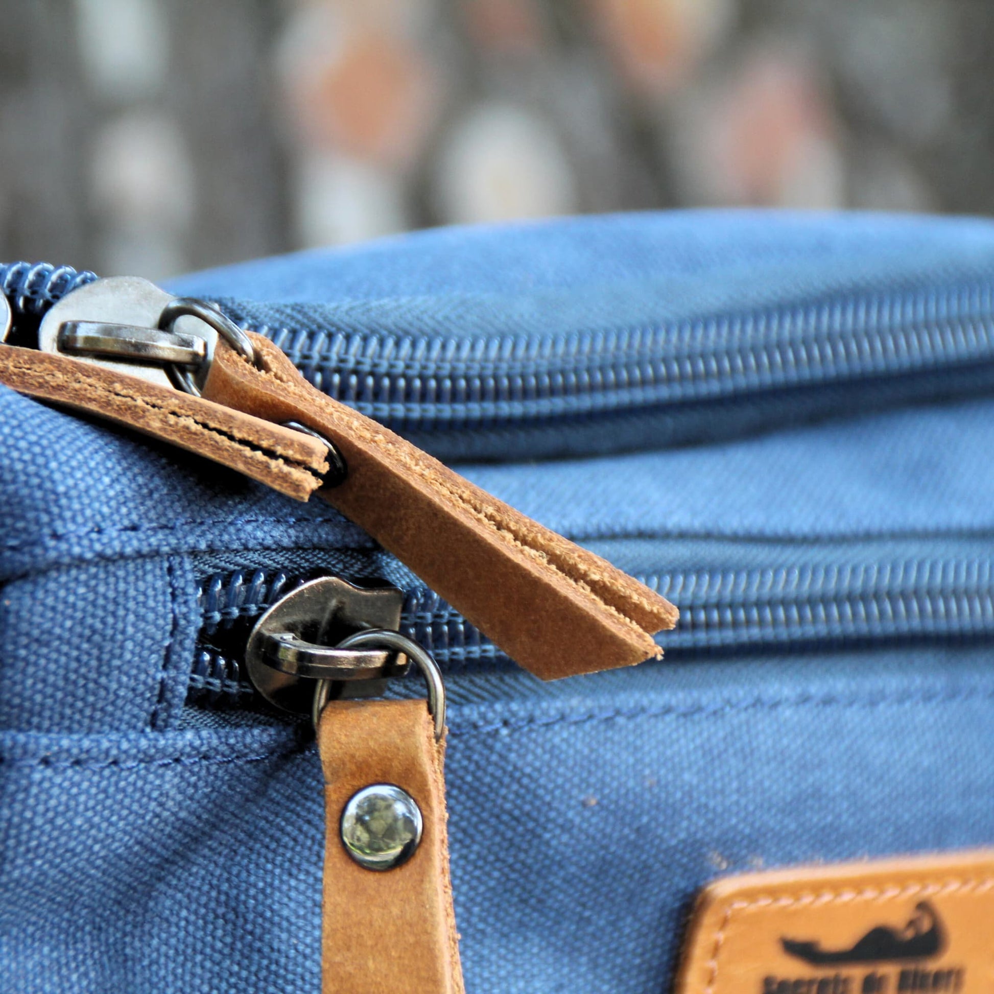 Zoom sur les finitions en cuir sur le zip de fermeture de la trousse de toilette. 