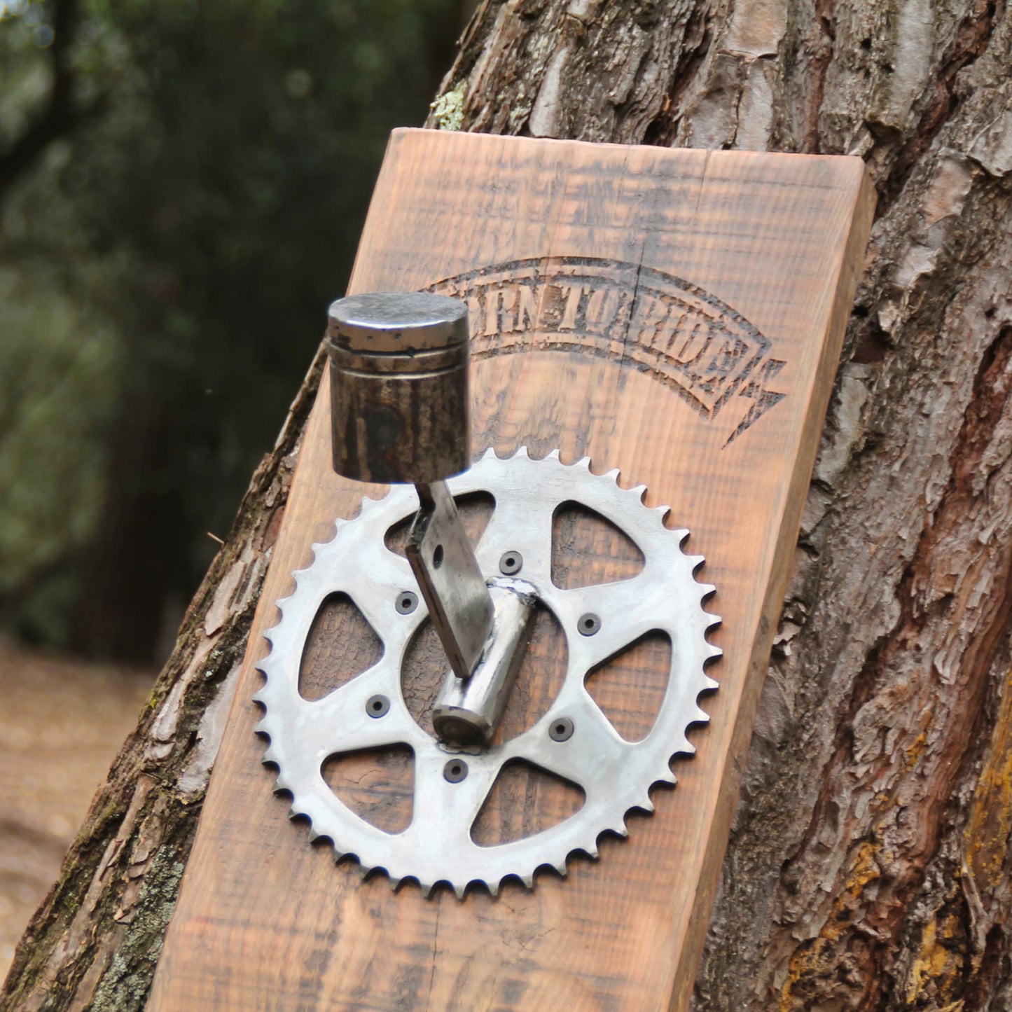 Zoom sur les détails du support de casque Born to Ride pour deux casques de moto. Pièces mécaniques recyclées (pistons, disque) et bois brut. 